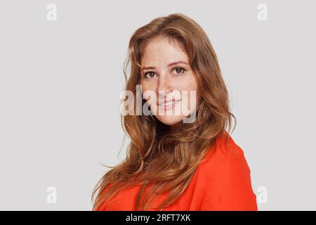 Porträt einer glücklichen Frau in roter Bluse, die auf weißem Hintergrund in die Kamera schaut Stockfoto