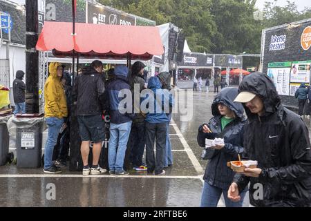 Lokeren, Belgien. 05. Aug. 2023. Die Abbildung zeigt Zuschauer, die während der Lokerse Feesten am Samstag, den 05. August 2023 in Lokeren im Regen eine Show mit Poncho und Regenschirm sehen. Das Festival findet vom 4. August bis 13. August statt. BELGA FOTO NICOLAS MAETERLINCK Kredit: Belga News Agency/Alamy Live News Stockfoto