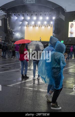 Lokeren, Belgien. 05. Aug. 2023. Die Abbildung zeigt Zuschauer, die während der Lokerse Feesten am Samstag, den 05. August 2023 in Lokeren im Regen eine Show mit Poncho und Regenschirm sehen. Das Festival findet vom 4. August bis 13. August statt. BELGA FOTO NICOLAS MAETERLINCK Kredit: Belga News Agency/Alamy Live News Stockfoto