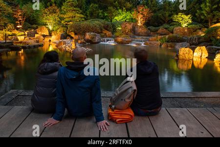 Augsburg, Deutschland. 05. Aug. 2023. Mit Decken ausgestattet, genießen die Menschen im Japanischen Garten die „Magie der Lichter“ im Botanischen Garten. Jeden Samstag, bis zum 13. August, gehen im Botanischen Garten unzählige Lichter in der Dämmerung an. Zu diesem Zweck ist der Botanische Garten bis Mitternacht geöffnet. Kredit: Stefan Puchner/dpa/Alamy Live News Stockfoto