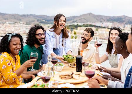 Eine Gruppe multiethnischer Freunde, die im Sommer ein Barbecue auf der Terrasse genießen Stockfoto