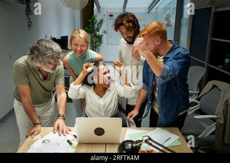 Eine Gruppe von Kollegen im Büro, die ihre Arme heben, um ein gutes neues zu feiern Stockfoto