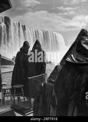 Niagarafälle, New York: 17. Mai 1937 zwei Flitterwöchler, die in Ölfässern gesunken sind, damit sie nicht vom Sprühnebel durchnässt werden, schauen Sie vom Deck der „Maid of the Mist“-Tour auf ihrer ersten Reise im Jahr 1937 in Richtung der majestätischen Horseshoe Falls. Stockfoto