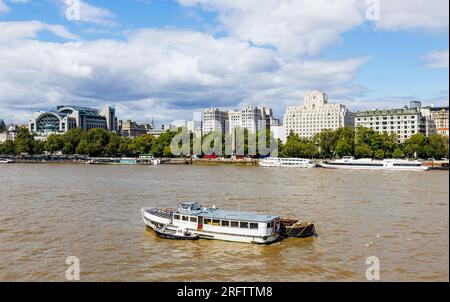 Blick von der Charing Cross Station entlang Victoria Embankment zum Shell Mex House und den festgemachten Flussbooten der Themse am Woods Quay London WC2 Stockfoto