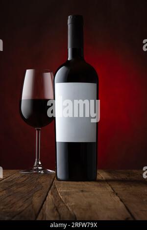 Werbespot aus Glas und Flasche Rotwein mit leerem Etikett auf rostbraunem Hintergrund. Modell, Vorderansicht Stockfoto