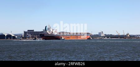 Großes Kohletransportschiff, das mit Schleppbooten in den Hafen gebracht wird. Newcastle Australien. Newcastle ist einer der weltweit größten Kohleexporthäfen in Th Stockfoto