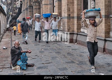 Träger mit Fischteller auf dem Kopf, vor dem Chhatrapati Shivaji Maharaj Terminus (CMST) in Mumbai, Indien, um die Tabletts mit dem Zug zu transportieren Stockfoto