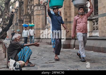 Träger mit Fischteller auf dem Kopf, vor dem Chhatrapati Shivaji Maharaj Terminus (CMST) in Mumbai, Indien, um die Tabletts mit dem Zug zu transportieren Stockfoto