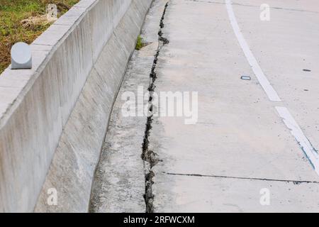 Risse auf der Straße gerissene Betonoberflächen weisen auf die Gefahr für Verkehrsteilnehmer und Reparaturen hin. Stockfoto