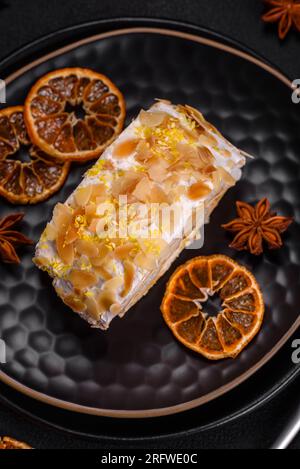 Köstliche, frische, süße Baiser-Brötchen mit Sahne, Mandelchips, Nüssen und Beeren in Scheiben auf dunklem Betonhintergrund Stockfoto