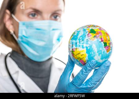 Weibliche Ärztin in schützender medizinischer Maske und Handschuhe hält Globus. Stockfoto
