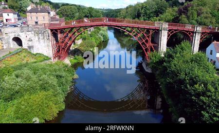 Luftaufnahme der historischen Ironbridge über den Fluss Severn, mit einer Reflexion des stillen Wassers. Ironbridge Gorge, Telford, Shropshire, Juli 2023 Stockfoto