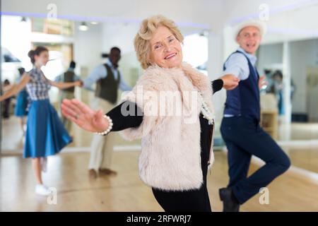 Ältere Frau und jüngerer Mann tanzen Schaukel im Studio Stockfoto