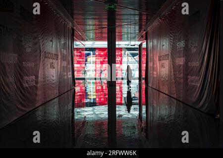 2023-07-29 Kiew, Ukraine. Weibliche Silhouette im Tunnel mit Reflexionen auf dem Boden im leeren Einkaufszentrum in Kiew. Stockfoto