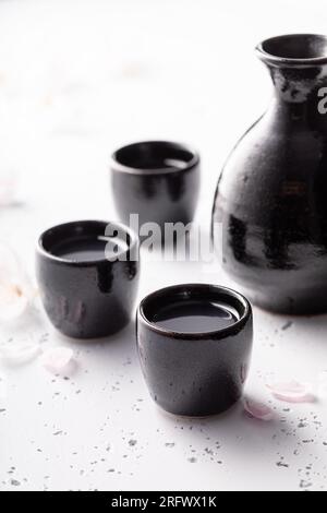 Spezieller japanischer Sake in schwarzer kleiner Keramik. Sake in Keramik serviert. Stockfoto