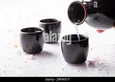 Ungefilterter japanischer Sake mit rosa Blüten. Die Methode der Alkoholausschüttung in Japan. Stockfoto