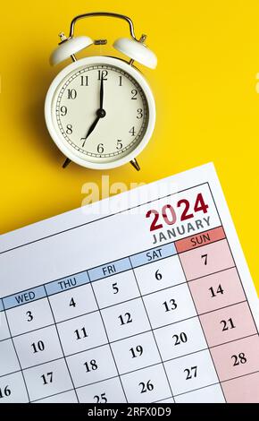 Uhr und Kalender für 2024 auf gelbem Hintergrund. Stockfoto