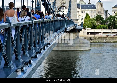 Ausblick auf die renovierte Kettenbrücke. Tourboot auf der Donau. Die Pest-Seite im Hintergrund. Sie wieder für die Öffentlichkeit zugänglich machen, Leute laufen. Stockfoto