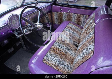 Klassischer amerikanischer Fahrzeuginnenraum mit Sitzen in Leopardenhaut. Sitzbezug im Auto mit Leopardenmuster Stockfoto