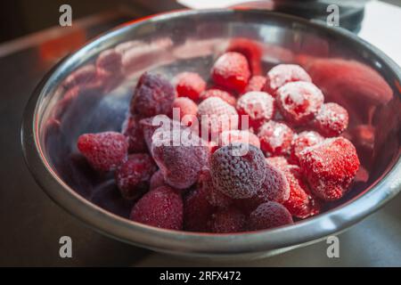 Nahaufnahme von gefrorenen Erdbeeren in einer Aluminiumschüssel auf einer Küchentheke. Stockfoto