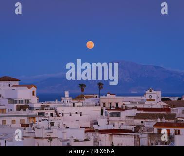 Vollmond über der Altstadt von Tarifa, Spanien, mit dem Berg Jebel Musa, Marokko im Hintergrund. Die Straße von Gibraltar trennt t Stockfoto