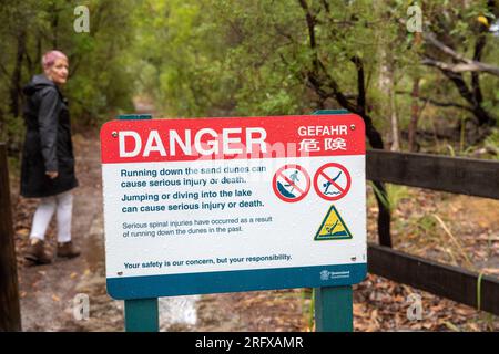 Fraser Island Woman Walks by Danger Schild auf dem Weg zum Lake Wabby warnt davor, nicht auf Sanddünen zu laufen, Queensland, Australien Stockfoto