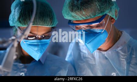 Nahaufnahme von professionellen Chirurgen mit blauen Masken im Operationssaal. Stockfoto