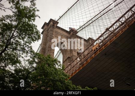 Erleben Sie den majestätischen Reiz der Brooklyn Bridge, ein architektonisches Wunderwerk am East River in New York City. Erleben Sie die Schönheit urbaner Engi Stockfoto