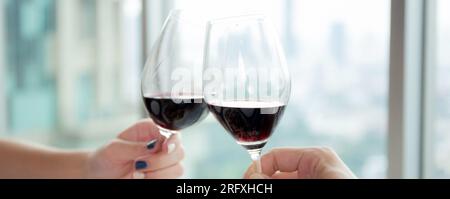 Die Hände eines jungen Paares, das sich mit einem Glas Wein in der Hand hält, jubeln im Restaurant zum Feiern zusammen, Mann und Frau treffen sich mit Romantikern und Narren Stockfoto