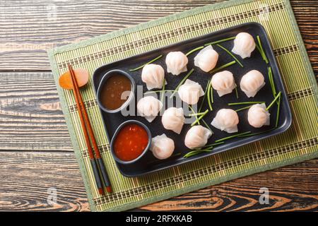 Traditionelle gedünstete chinesische Teigtaschen Dim Sums Har Gow mit Garnelen serviert mit Sauce Nahaufnahme auf dem Tisch. Horizontale Draufsicht von oben Stockfoto