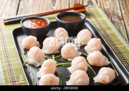 Chinesische Dim-Sum-Har-Gow-Teigtaschen mit Garnelen, serviert mit Sauce-Nahaufnahme auf dem Tisch. Horizontal Stockfoto