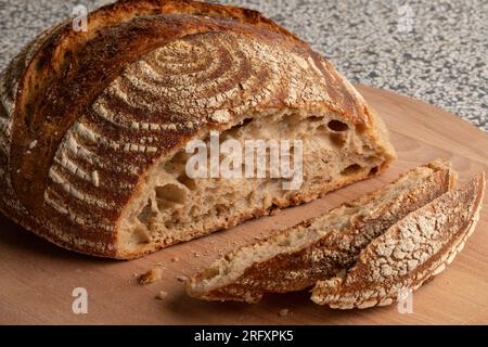 Traditioneller hausgemachter Laib mit Sauerteigbrot und Scheiben auf einem Schneidebrett aus nächster Nähe Stockfoto