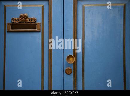 Hellblaue Holztür im Vintage-Stil mit antikem Bronzegriff und Buchstabenschlitz in Taormina Sizilien, Italien. Stockfoto