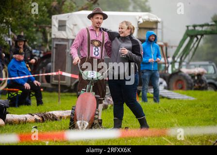 Braunsbach Steinkirchen, Deutschland. 06. Aug. 2023. Michael Sack von Eberbach am Neckar, Teilnehmer der Weltmeisterschaft für Bergmäher, ist der erste, der mit seinem Bergmäher die Ziellinie überquert hat und von seiner Freundin begrüßt wird. Nachdem er alle Punkte gezählt hat, gewinnt er am Ende auch die Weltmeisterschaft und wird Weltmeister. Kredit: Christoph Schmidt/dpa/Alamy Live News Stockfoto