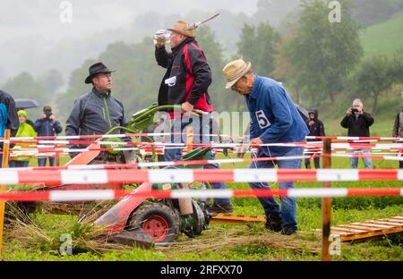 Braunsbach Steinkirchen, Deutschland. 06. Aug. 2023. Die Teilnehmer der Mountain Mower World Cup laufen mit ihren Bergmähern über einen Teil des Wettkampfkurses. Das Ziel an diesem Streckenpunkt ist es, auf einer Wippe mit den Bergmähern ins Gleichgewicht zu kommen und so schnell wie möglich einen halben Liter Bier zu trinken. Kredit: Christoph Schmidt/dpa/Alamy Live News Stockfoto