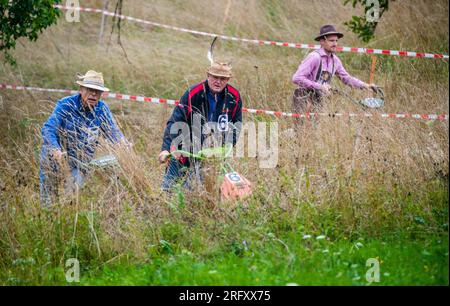 Braunsbach Steinkirchen, Deutschland. 06. Aug. 2023. Teilnehmer der Mountain Mower World Cup fahren mit ihren Bergmähern einen Teil des Rennplatzes und mähen dabei hohes Gras. Kredit: Christoph Schmidt/dpa/Alamy Live News Stockfoto