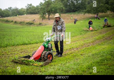 Braunsbach Steinkirchen, Deutschland. 06. Aug. 2023. Ein Teilnehmer der Mountain Mower World Championship läuft mit seinem Bergmäher über einen Teil der Rennstrecke. Kredit: Christoph Schmidt/dpa/Alamy Live News Stockfoto