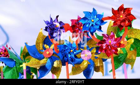 Nahaufnahme, viele mehrfarbige Windmühlen. Farbenfrohes Spielzeug Windmühlen drehen sich sehr schnell auf Wind. Hochwertiges Foto Stockfoto