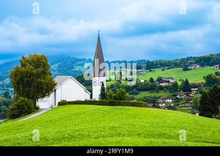 Faulensee-Dorf mit weißer Kirche und typischen schweizer Häusern auf Hügeln nahe Spiezstadt am Thunersee im Berner Oberland im Kanton Bern Stockfoto