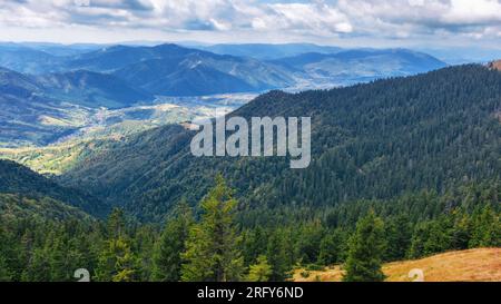 Berglandschaft der karpaten im Herbst. Bewaldete Hügel, die in das ferne ländliche Tal hinunterziehen. Wunderschöne Landschaft an einem bewölkten Tag mit Wolken Stockfoto