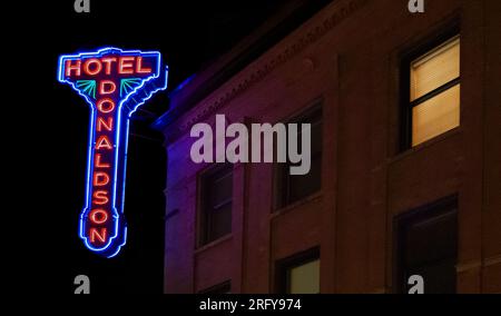 Das historische Hotel Donaldson Neonschild und ein Fenster mit eingeschaltetem Licht, spät nachts im Zentrum von Fargo, North Dakota. Stockfoto
