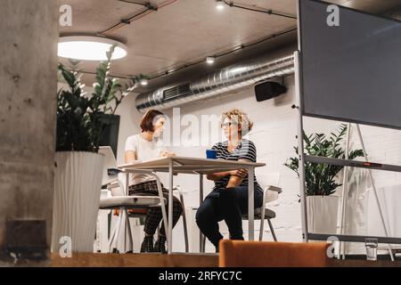 Zwei Kollegen diskutieren und tauschen Ideen aus, während sie an einem Projekt arbeiten Stockfoto