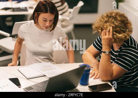 Zwei Frauen, die ein Diagramm planen und anschauen, während sie im Büro arbeiten Stockfoto