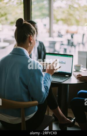 Drei Studenten sitzen und plaudern in einer Café-Bar über das neueste bevorstehende Projekt Stockfoto