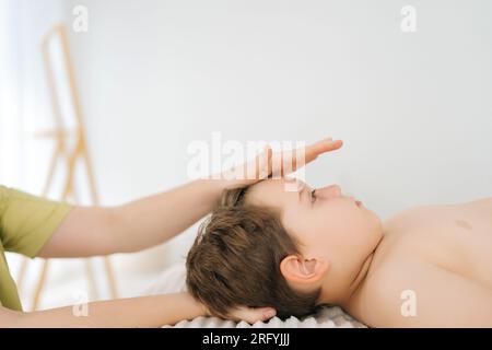 Nahaufnahme einer nicht erkennbaren professionellen Physiotherapeutin, die sich an einem 5-jährigen Jungen in der Osteopath-Schrank umstellt Stockfoto