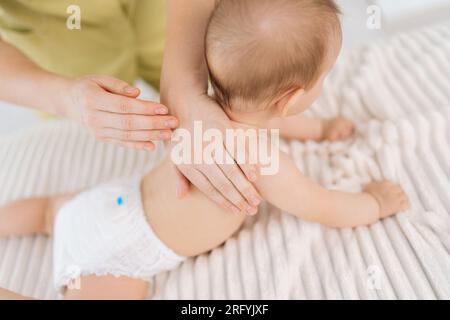 Nahaufnahme von oben: Liebevolle Mutterhände massieren kleines Baby. Nahaufnahme der unbekannten Masseuse weibliche Hände, die Neugeborene massieren. Stockfoto