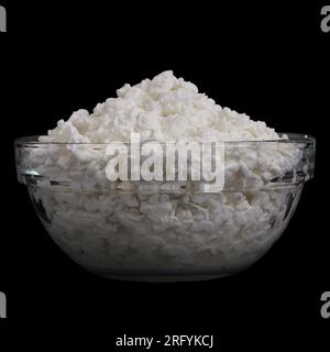 Hüttenkäse in Glasschüssel isoliert auf schwarzem Hintergrund. Seitenansicht eines europäischen Frikadellen-Snacks Stockfoto