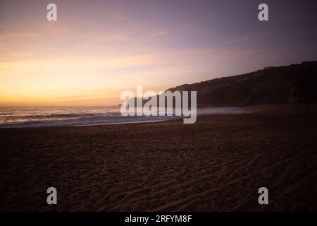 Genießen Sie den Zauber von Nazarés atemberaubender Landzunge, während die Sonne sanft unter den Horizont fällt und ein warmes und magisches Licht ausstrahlt Stockfoto