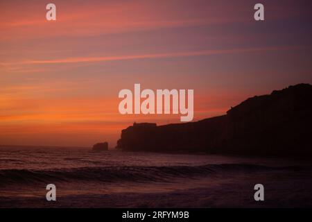 Genießen Sie den Zauber von Nazarés atemberaubender Landzunge, während die Sonne anmutig unter den Horizont fällt und ein warmes und magisches Licht über diesem C wirft Stockfoto