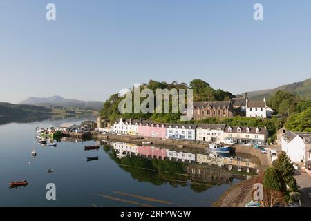 Der Klumpen und die bunten Gebäude in der Quay Street in Portree auf der Isle of Skye spiegeln sich an einem ruhigen Sommermorgen in Loch Portree wider Stockfoto